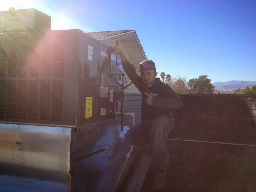 HVAC technician performing Air Duct Cleaning on a rooftop unit in Portsmouth