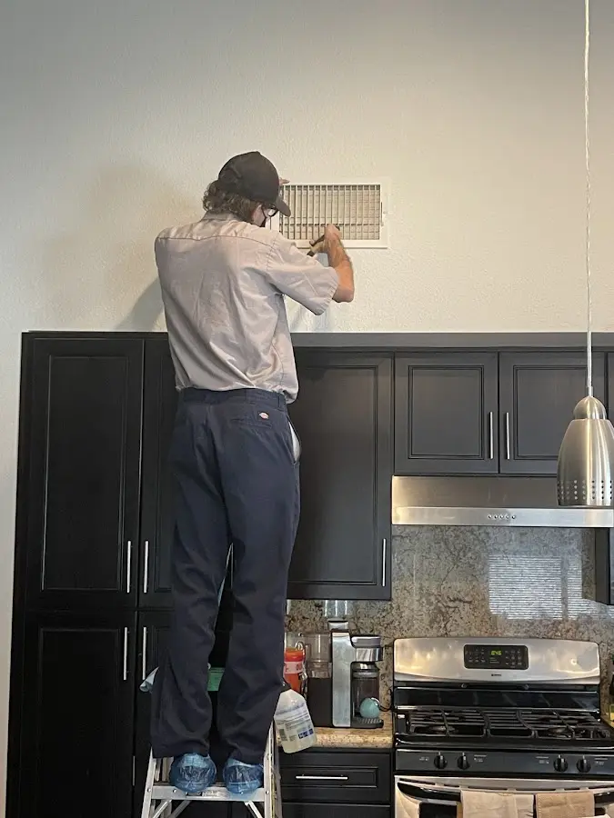 Technician inspecting an air vent during HVAC service in Portsmouth